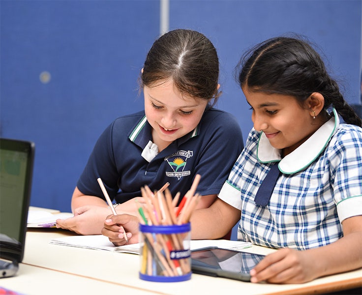 Two students drawing with pencils